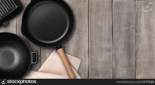 Empty cast iron frying pan on dark culinary background, view from above. Food background with free space for text. Empty cast iron frying pan. Top view with copy space