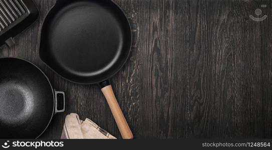 Empty cast iron frying pan on dark culinary background, view from above. Food background with free space for text. Empty cast iron frying pan. Top view with copy space