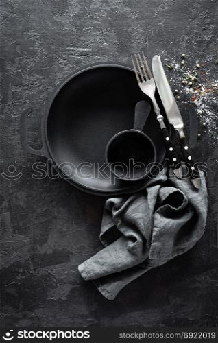 Empty cast-iron pan with cutlery on dark background for restaurant menu, top view