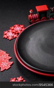 Empty ceramic black plate with christmas decoration e≤ments on holiday textured concrete background