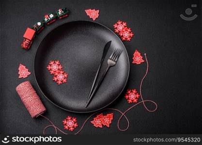Empty ceramic black plate with christmas decoration elements on holiday textured concrete background