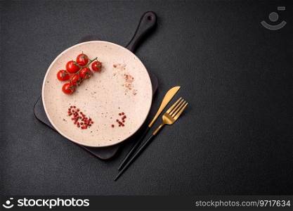 Empty ceramic plate on a dark textured background. Preparing kitchen utensils for a family dinner