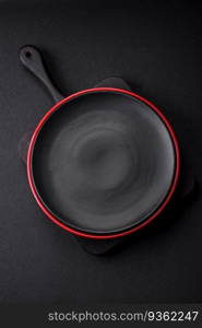 Empty ceramic plate on dark textured concrete background. Cutlery on the kitchen table