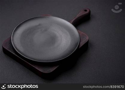 Empty ceramic round plate on dark textured concrete background. Cutlery, preparation for dinner
