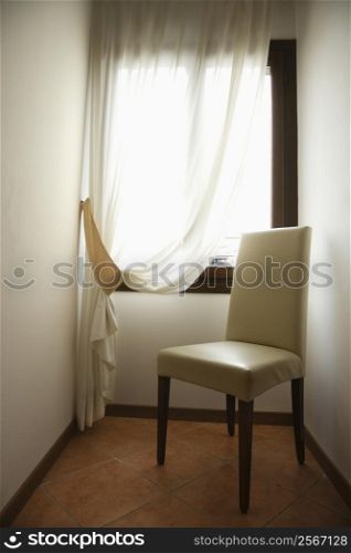 Empty chair by window with drapes in Venice, Italy.