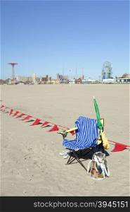 empty chair with towel on sunny coney island beach waits for sitter to return