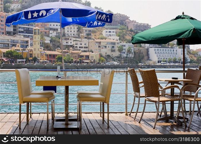Empty chairs and tables in a restaurant with buildings in the background, Ephesus, Turkey