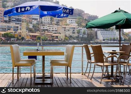 Empty chairs and tables in a restaurant with buildings in the background, Ephesus, Turkey
