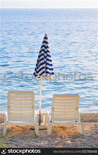 empty chairs on beach with umbrella