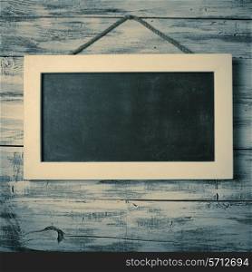 Empty chalkboard on the rope attached to shabby white wooden background