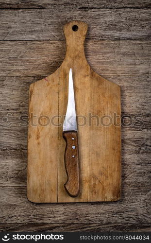 Empty chopping board with a knife on a distressed grunge wooden table