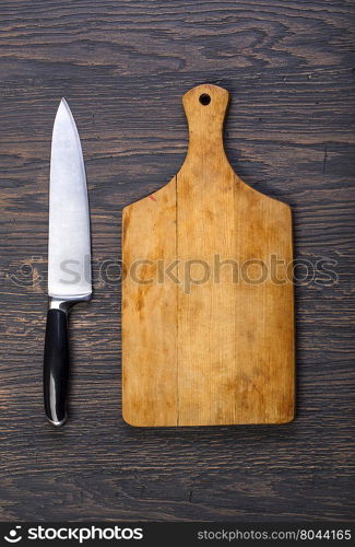 Empty chopping board with a knife on a distressed grunge wooden table in a rustic kitchen,