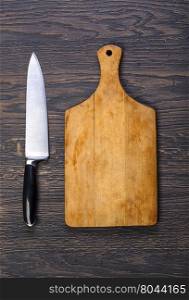 Empty chopping board with a knife on a distressed grunge wooden table in a rustic kitchen,