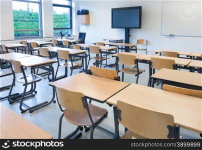 Empty classroom with tables and chairs in school building