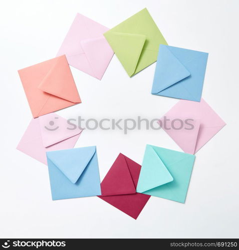 Empty colorful hndcraft envelopes in the shape of round frame on a light gray background with copy space.. Round frame of colored craft blank envelopes on a light background.