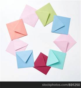 Empty colorful hndcraft envelopes in the shape of round frame on a light gray background with copy space.. Round frame of colored craft blank envelopes on a light background.