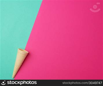 empty conical baked waffle cup on a green-pink background, place for text, flat lay