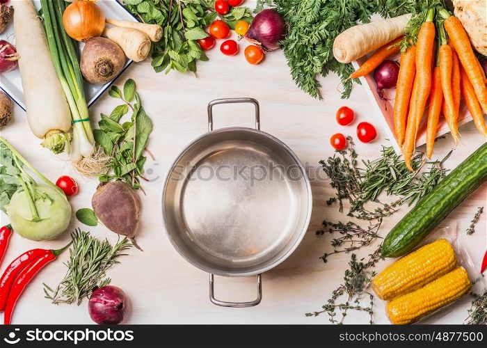 Empty cooking pot and organic vegetables selection for tasty and healthy cooking, top view, place for text. Vegan or vegetarian food concept