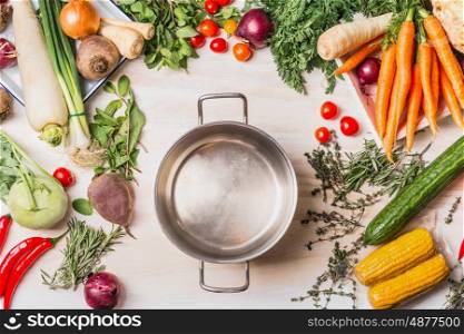 Empty cooking pot and organic vegetables selection for tasty and healthy cooking, top view, place for text. Vegan or vegetarian food concept