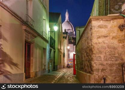 Empty cozy street and the Sacre-Coeur Basilica at night, quarter Montmartre in Paris, France. Montmartre in Paris, France