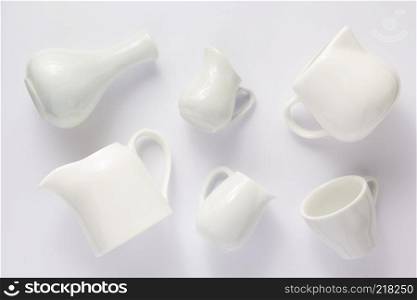 empty cream jug and cup on white background, top view