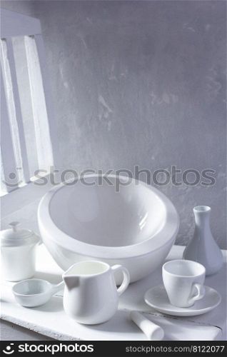 Empty crockery set on wooden chair. White kitchen dishware near grey wall background texture