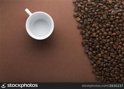 Empty cup on brown background with coffee beans. Empty white cup on brown background with coffee beans