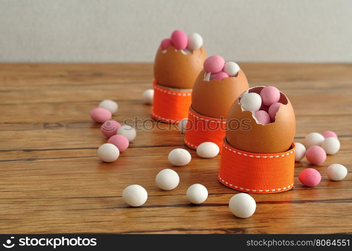 Empty egg shells filled with pink and white candy displayed on a table for decorating an easter table