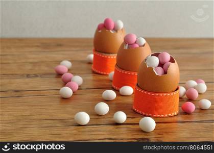 Empty egg shells filled with pink and white candy displayed on a table for decorating an easter table