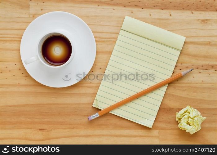 empty espresso coffee cup, notepad and pencil on pine wood table