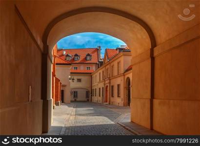 Empty gateway and old paved street with lantern in the Old Town of Warsaw in the summer sunny day, Poland