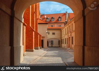 Empty gateway and old paved street with lantern in the Old Town of Warsaw in the summer sunny day, Poland