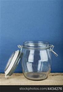 Empty glass jar with cap hold with metal wire on the wooden floor