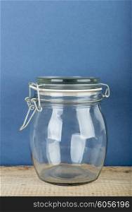 Empty glass jar with cap hold with metal wire on the wooden floor