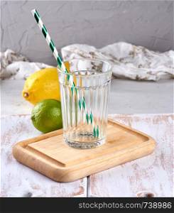 empty glass with facets and green cocktail tube on a wooden board