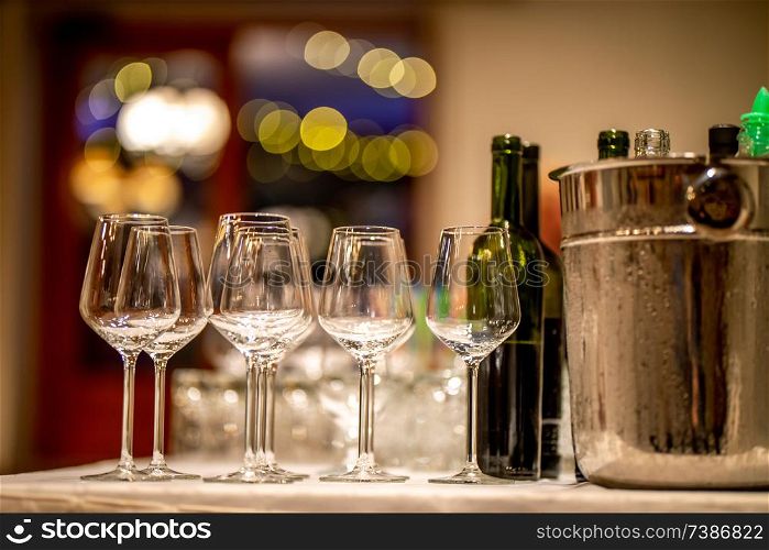 Empty glasses, wine bottles and bucket with ice on table in restaurant. Ice bucket, wine glasses and bottles arranged on the table for wedding reception.