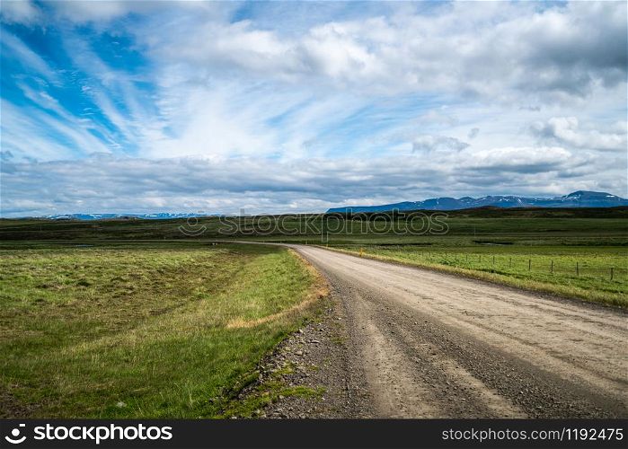 Empty gravel dirt road through countryside landscape and grass field. Nature off road travel trip for four-wheel-drive vehicle.