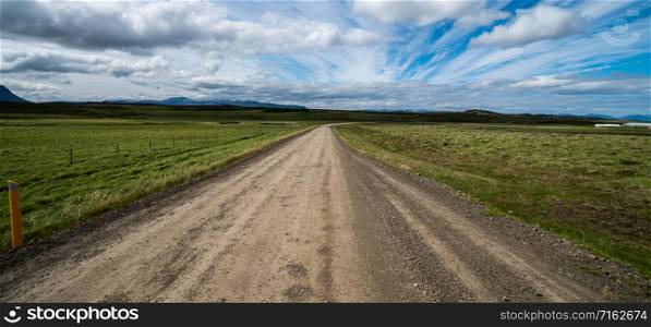 Empty gravel dirt road through countryside landscape and grass field. Nature off road travel trip for four-wheel-drive vehicle.
