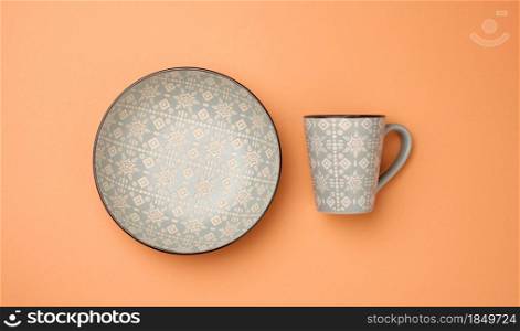 empty gray ceramic soup plate and empty cup on a orange background, utensils, top view