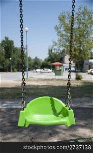 Empty green swing with chain. Vertical image