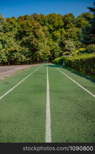 Empty green treadmill in artificial turf on a clear sunny day.. Treadmill in sport field with green grass and sunlight.