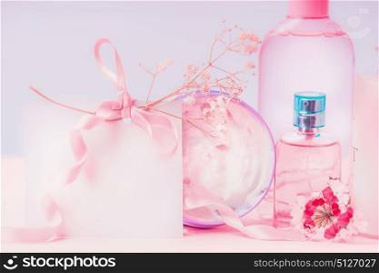 Empty greeting card laid and pink cosmetic products setting. Invitation, coupon, discount and sale. Beauty, skin and hair care concept