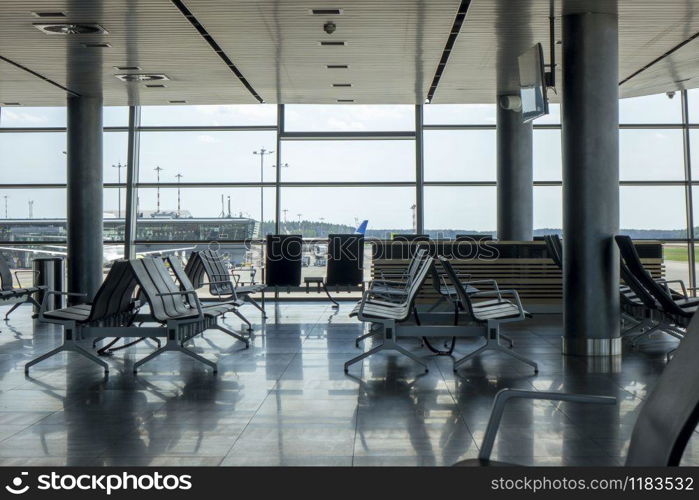 Empty hall at airport with comfortable chairs for waiting departure. Travel and transportation concept.. Contemporary airport hall interior with empty chairs.