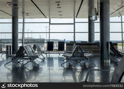 Empty hall at airport with comfortable chairs for waiting departure. Travel and transportation concept.. Contemporary airport hall interior with empty chairs.