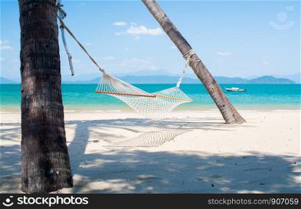 empty hammock tied to coconut palm tree at the beach