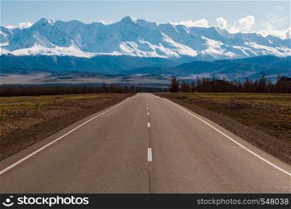 empty highway leading to the mountains with snow caps. Altai mountains landscape.. empty highway leading to the mountains with snow caps. Altai mountains landscape