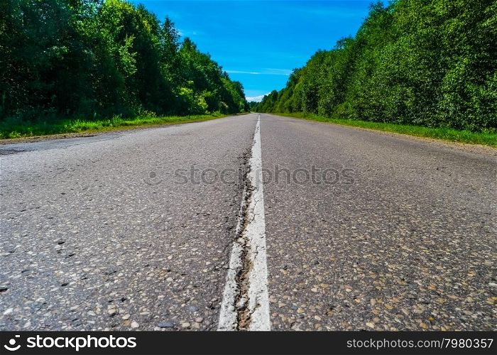 Empty highway with green forest on both sides, crack in asfalt