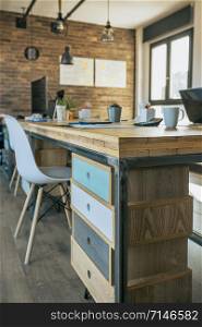 Empty industrial style office with wooden chest of drawers in the foreground