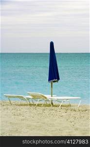 Empty lounge chair and a folded beach umbrella on the beach