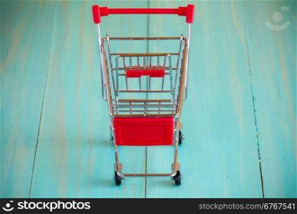 Empty mini shopping cart against wooden background